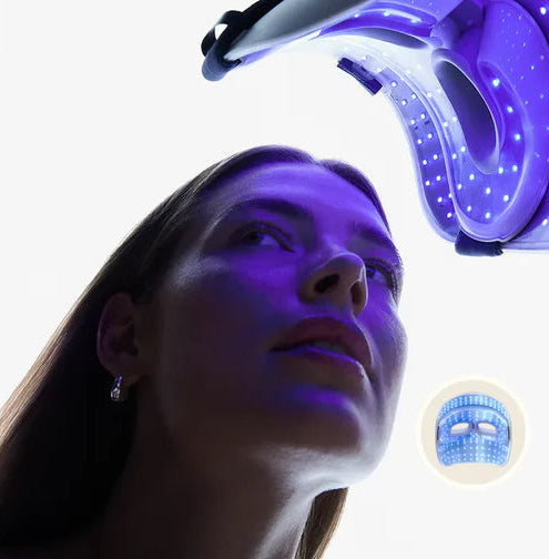 Woman receiving LED face mask treatment with a device above her head on a white background.